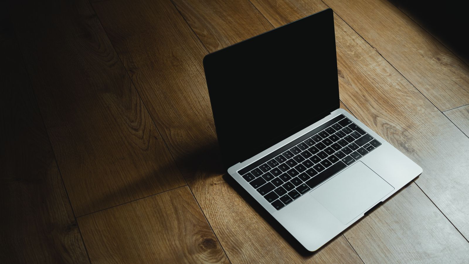 MacBook Pro aperto su piano in legno